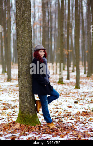 Young girl in outdoor full length, propping on a tree in a forest Stock Photo