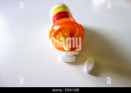 A prescription bottle lying on its side with pills spilling out. White background. USA. Stock Photo
