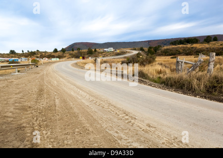 Dirt road winding into the distance with an old fence in the foreground Stock Photo