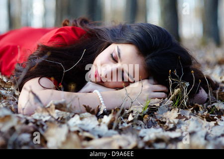 Portrait of a beautiful woman sleeping on the ground in the woods Stock Photo