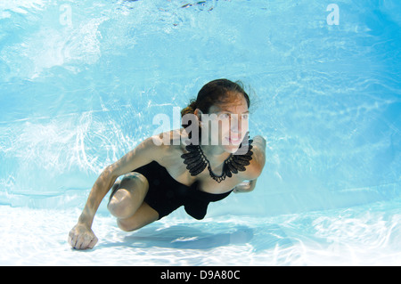 A young woman in evening dress floats underwater Model release available Stock Photo