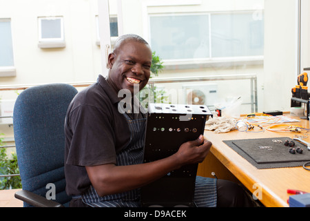 senior African man assembly electronic equipment in workshop Stock Photo