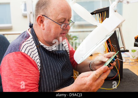 senior technician checking electrical circuit board under electronic magnifying glass Stock Photo