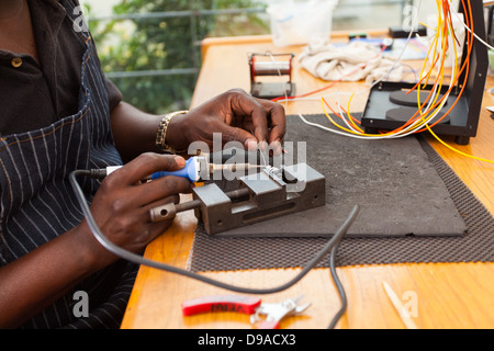 senior African electrician using soldering iron repair a push button Stock Photo