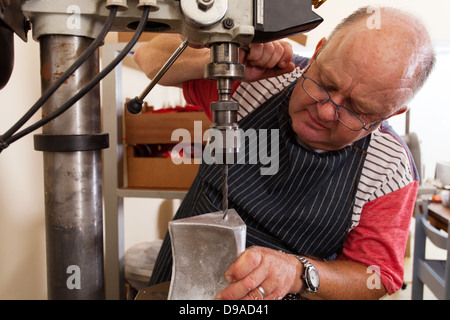 senior metal worker using industrial drilling machine in workshop Stock Photo