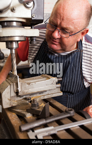 senior man using industrial drilling machine in workshop Stock Photo