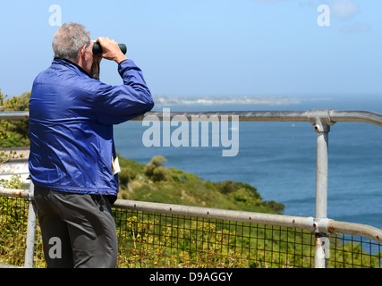Man looking out to sea with binoculars Stock Photo