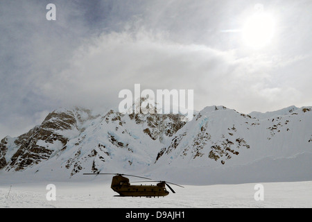 A US Army CH-47F Chinook helicopter waits in a snow-covered field near the Kahiltna Glacier base camp April 26, 2013 in Denali National Park, AK. The camp supports mountaineers attempting to climb nearby Mount McKinley. Stock Photo