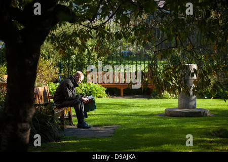A student sits on a bench quietly studying in the grounds of Trinity College Dublin in the Republic Of Ireland Stock Photo