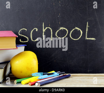 stationery (pen, pencil, ruler, compass) and a book on black school board background Stock Photo