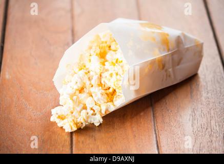 Delicious popcorn in paper pack on wood table Stock Photo
