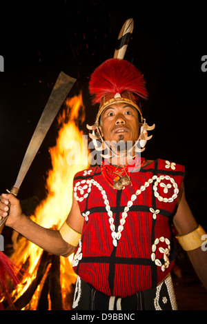 Naga tribesman holding a machete in front of fire during the annual Hornbill Festival at Kisama, Kohima, Nagaland, India Stock Photo