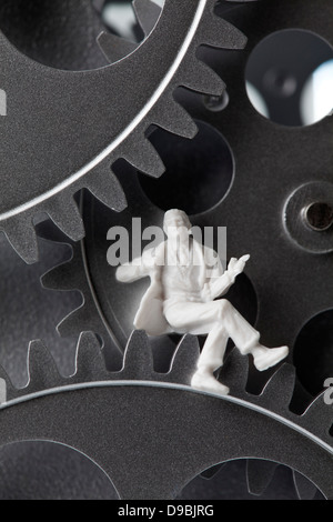 Figurine sitting on gear wheels, close up Stock Photo