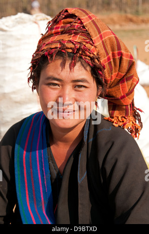 Young Pa-O woman wearing orange checked traditional headdress smiling at the camera in a market Myanmar (Burma) Stock Photo