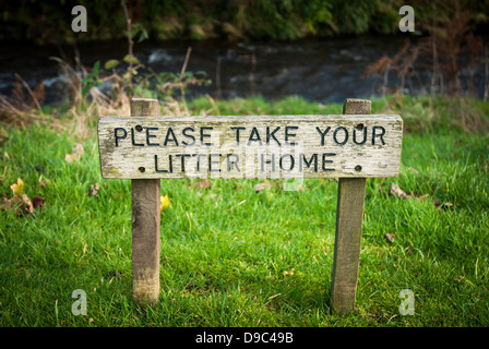 Wooden sign in countryside asking to take litter home Stock Photo