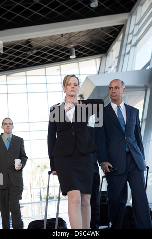 Businesspeople walking through airport with suitcases Stock Photo