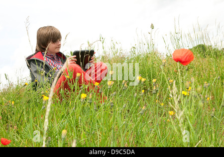 young male boy using ipad mini tablet computer in countryside Stock Photo