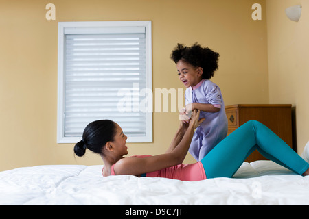 Mother and daughter playing on bed Stock Photo