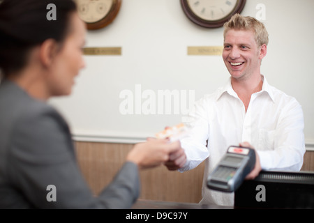 Woman paying young man on hotel reception Stock Photo