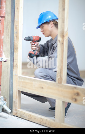 Female laborer using electric drill on construction site Stock Photo