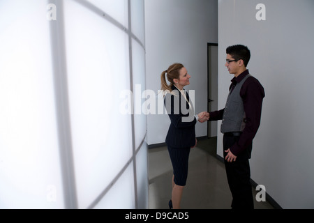 Young businesspeople in corridor shaking hands Stock Photo