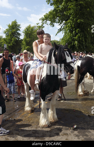 A gypsy mother and son ride their horse bareback after washing it in the River Eden at Appleby Horse Fair, in Cumbria, England