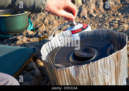 A hiker cooking on a camping stove on the summit of a mountain in the Lake District. Stock Photo