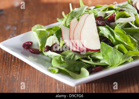 Gourmet artisan spinach, cranberry and pear salad sitting on a rustic wooden table in low light, ready to eat. Stock Photo