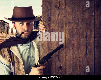 Bad gunman in the old wild west indicates with the gun a wooden plank Stock Photo