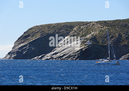 Rocky coast with Cala Nans lighthouse in background and a catamaran, Mediterranean sea, Cadaques, Catalonia, Costa Brava, Spain Stock Photo
