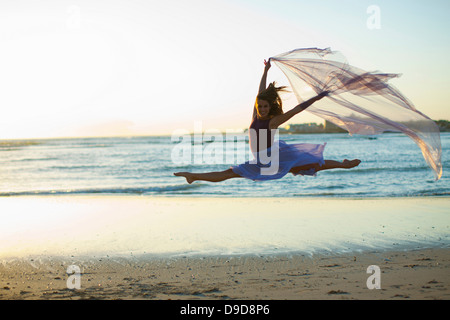 Young woman dancing on sunlit beach Stock Photo