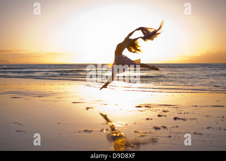 Young woman dancing on sunlit beach Stock Photo