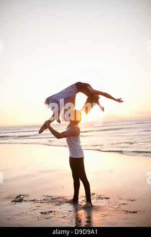 Young man lifting dancing partner on sunlit beach Stock Photo