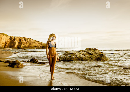 Young woman in bikini walking along beach Stock Photo