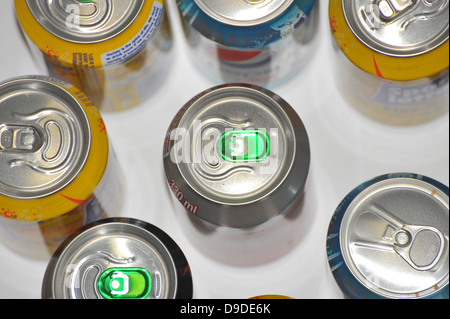 The tops of a variety of cans of fizzy pop photographed against a white background. Stock Photo