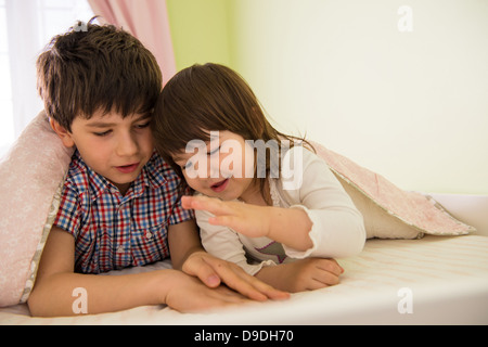 Brother and sister playing game in bed Stock Photo