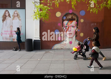 Brixton, London: 18th June 2013 - A mural of iconic musician and singer David Bowie has appeared on the wall of Morleys department store in Brixton, Lambeth, south London. The Bowie face is sourced (by artist James Cochran, aka Jimmy C) from the cover of his 1973 album Aladdin Sane at the height of his 1970s fame. The pop icon lived at 40 Stansfield Road, Brixton, from his birth in 1947 until 1953. This cover appeared in Rolling Stone’s list of the 500 greatest albums of all time, making #277. Credit: Richard Baker / Alamy Live News