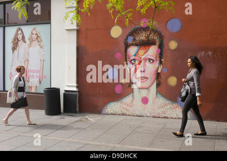 Brixton, London: 18th June 2013 - A mural of iconic musician and singer David Bowie has appeared on the wall of Morleys department store in Brixton, Lambeth, south London. The Bowie face is sourced (by artist James Cochran, aka Jimmy C) from the cover of his 1973 album Aladdin Sane at the height of his 1970s fame. The pop icon lived at 40 Stansfield Road, Brixton, from his birth in 1947 until 1953. This cover appeared in Rolling Stone’s list of the 500 greatest albums of all time, making #277. Credit: Richard Baker / Alamy Live News