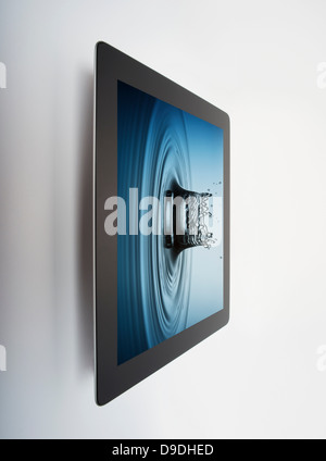 Digital tablet with crown shaped water drop splash on screen Stock Photo
