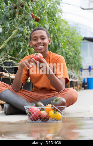 Boy sitting cross legged holding ripe tomato
