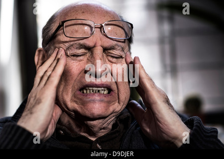 Senior man with eyes closed, wearing glasses, looking stressed Stock Photo