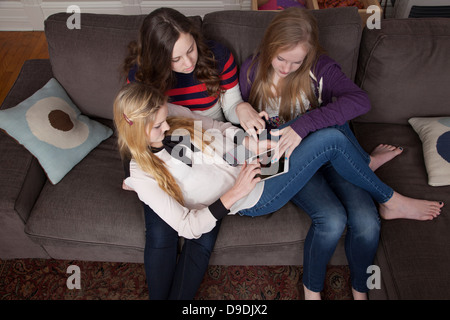 Girls sitting on sofa using digital tablet Stock Photo