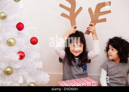 Two girls preparing for Christmas, playing with cardboard reindeer antlers