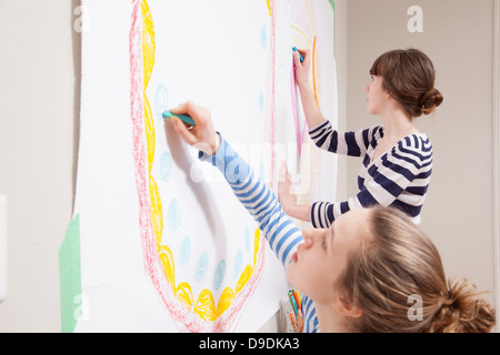 Girls drawing mural on wall Stock Photo