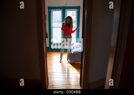 Teenager standing in bedroom listening to MP3 player Stock Photo