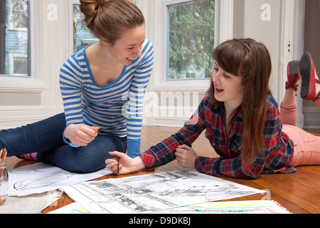 Girls lying on floor drawing pictures Stock Photo