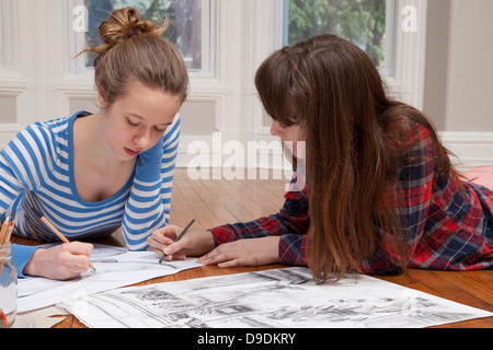 Girls lying on floor drawing pictures Stock Photo
