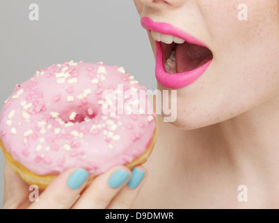Woman wearing pink lipstick eating doughnut