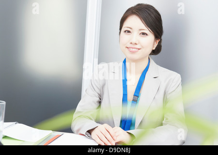 Portrait of woman at desk smiling Stock Photo