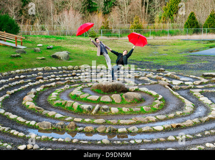 Mid adult dancers performing with red umbrellas in stone circle Stock Photo